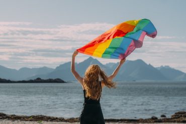Kvinne med regnbueflagg på stand i Lofoten