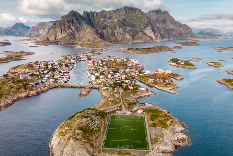 Bilde av Henningsvær med fotballbane i havgapet.